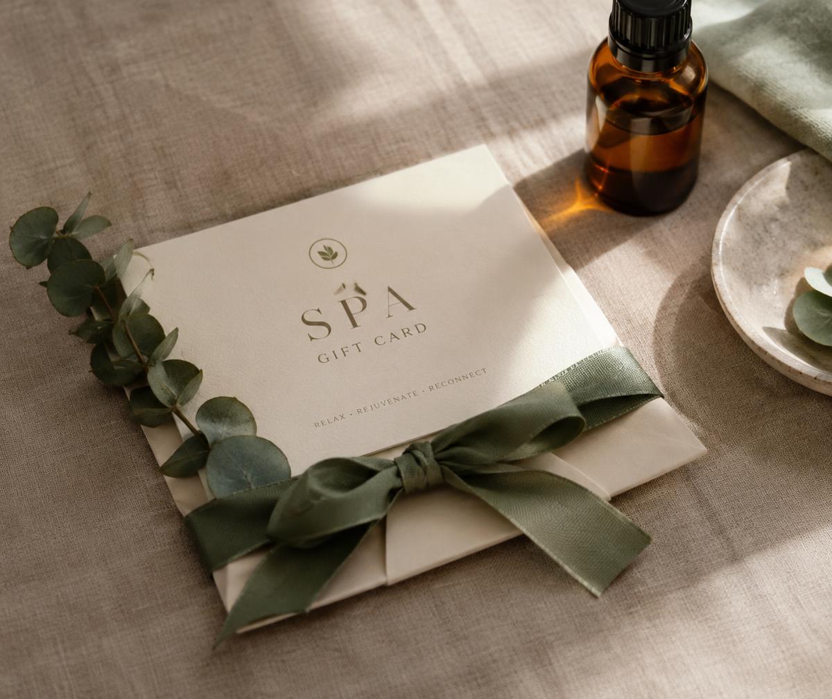 Spa gift card wrapped with a sage ribbon beside eucalyptus
